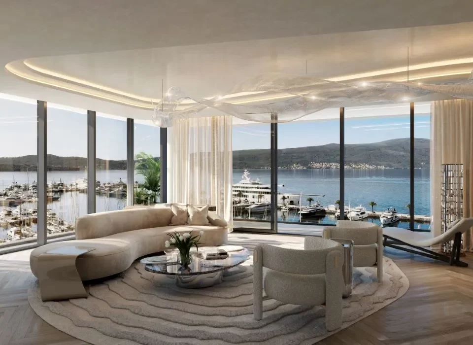 Luxurious waterfront living room with expansive floor-to-ceiling windows offering panoramic views of a marina, featuring modern, curved furnishings, a chic glass coffee table, and elegant lighting that accentuates the airy, sophisticated ambiance.